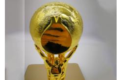 China Shiny Gold Plated Custom Trophy Cup With The Statue Holding The Ball Design supplier